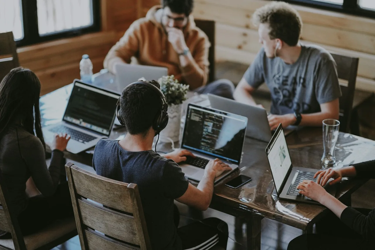 Developers collaborating around a table with laptops