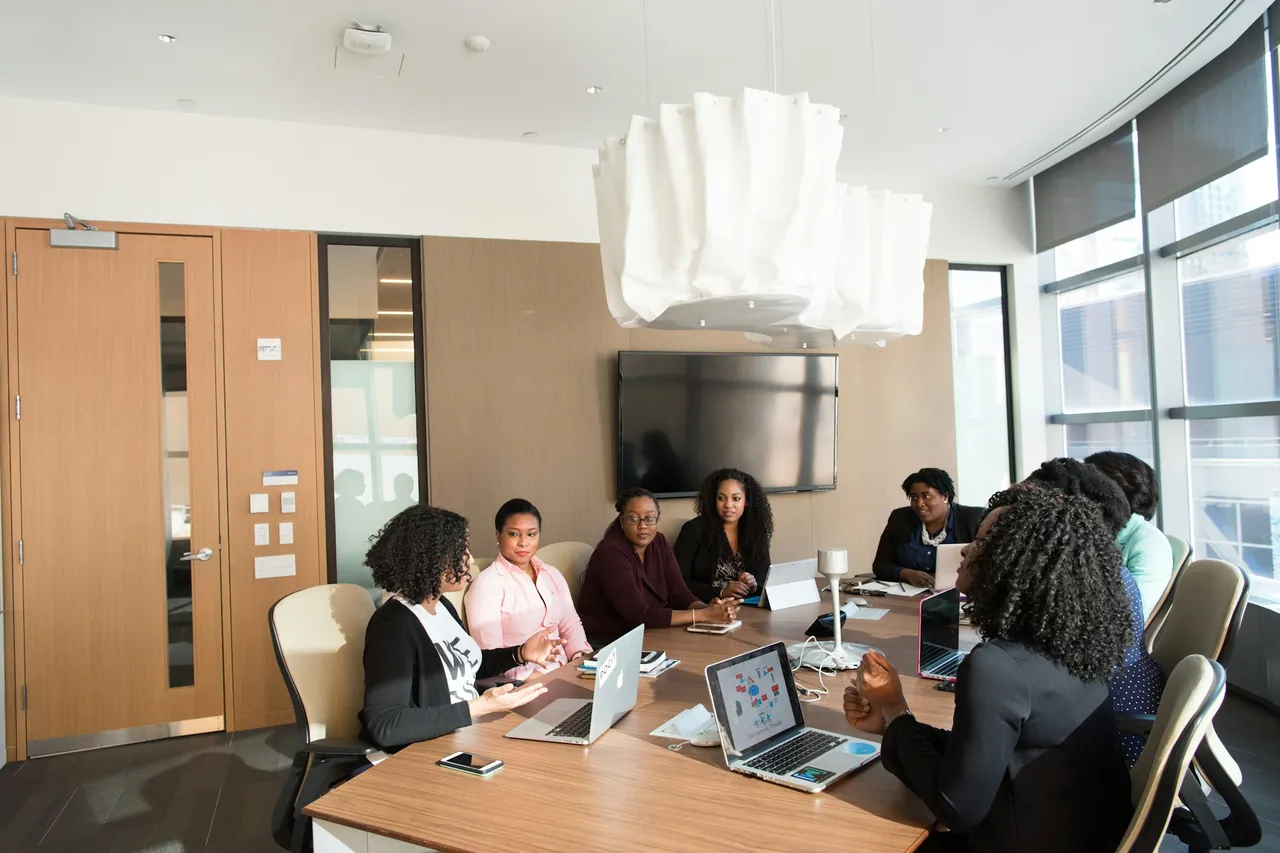 A team meeting around a table with laptops in a bright meeting room